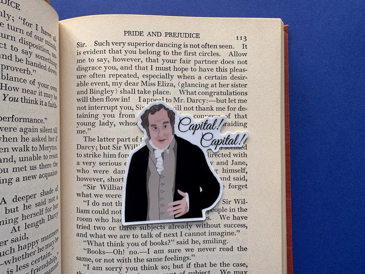 A cartoon of Sir William Lucas from Pride and Prejudice 1995 with the text 'Capital! Capital!'. The sticker is resting on an open book over a blue background.
