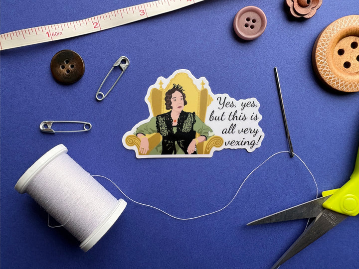 A cartoon of Lady Catherine from BBC Pride and Prejudice 1995 with the text 'yes, yes, but this all very vexing!'. She is sitting in a gold chair and wearing a green dress. The sticker is on a blue background surrounded by small sewing notions.