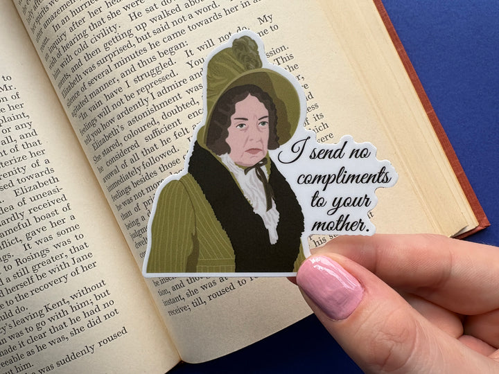 A cartoon of Lady Catherine from Pride and Prejudice 1995 with the text 'I send no compliments to your mother'. Held above an open book resting on a blue background.