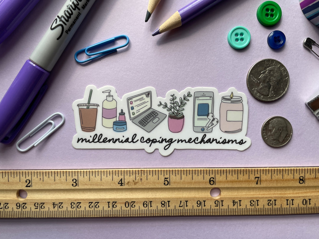 A sticker of a cartoon of a series of items including a candle, laptop, houseplant, iced coffee, lotion, and phone above the words "millennial coping mechanisms" is shown on a purple background surrounded by small objects.