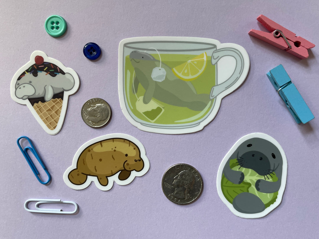 Four manatee stickers on a purple background surrounded by small objects.